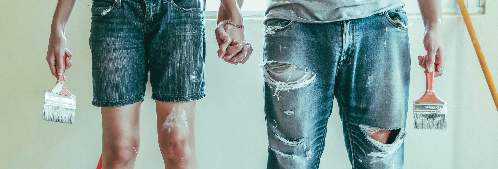 Two Paint Splattered Adults holding hands and paint brushes