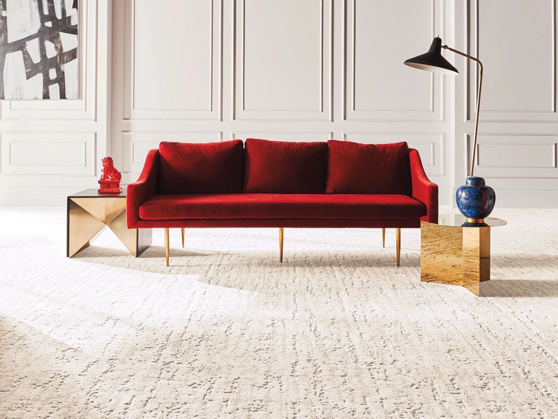 Bright living room with red velvet couch and beige carpet from Essex Paint and Carpet in the Essex Junction, VT area